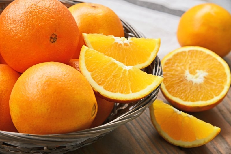 A lot of Navel Orange full and slice in basket on wooden background.